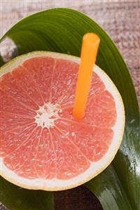 Half a pink grapefruit with a straw