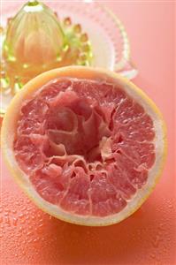 Squeezed pink grapefruit in front of citrus squeezer