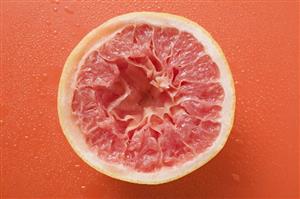 Squeezed pink grapefruit on orange background