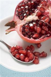 Half a pomegranate and spoonful of pomegranate seeds