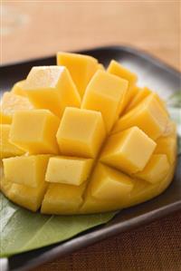 Diced mango still attached to the skin on brown plate