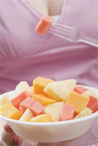 Woman eating exotic fruit salad