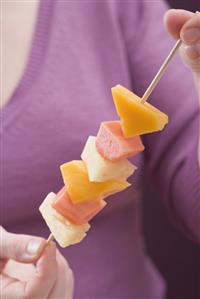 Woman holding exotic fruit skewer