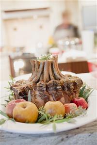 Roast rack of pork with apples, woman in background