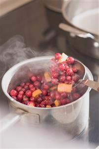 Making cranberry sauce: boiling cranberries and oranges