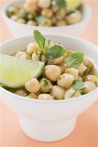 Chick-peas with lime wedges and herbs (close-up)