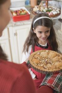 Woman holding apple tart, girl in background