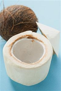 The flesh of a coconut in front of whole coconut