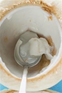 Coconut, shelled and hollowed out, with spoon (close-up)