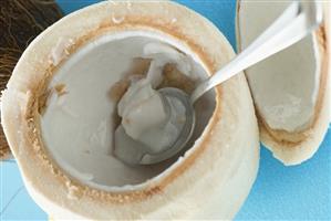 Coconut, shelled and hollowed out, with spoon