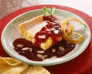 A piece of lemon cake with plum sauce & powdered sugar