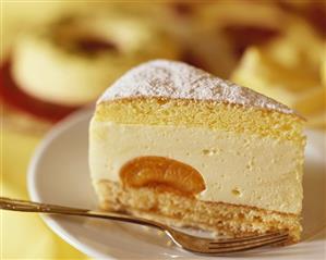 A piece of cheesecake with apricots on plate and fork