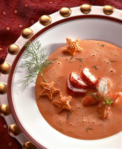 Cream of lobster soup with sesame stars & dill on a plate