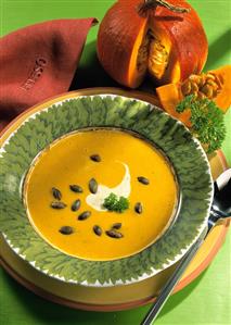 Pumpkin Cream Soup with Creme Fraiche and roasted Pumpkin Seeds in Bowl