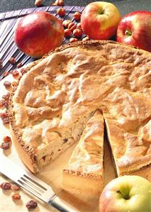 Wholemeal apple pie on wooden plate with apples