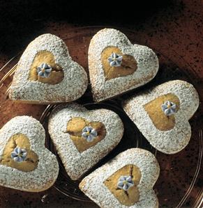 Heart-shaped sponge cakes with icing sugar & sugar violets