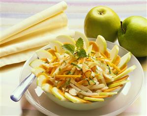 Raw carrots and apple with nuts and mint in bowl