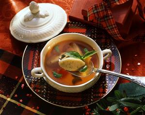 Clear tomato soup with basil dumplings in soup plate