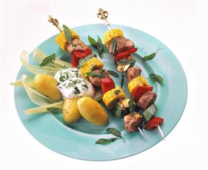 Meat & vegetable kebabs on plate with jacket potatoes & quark