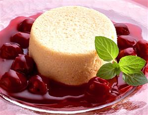 Semolina pudding with cherry sauce, garnished with mint