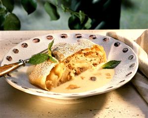 A piece of apple strudel with custard on plate