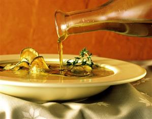 Olive Oil Pouring into a Bowl of Zucchini Soup