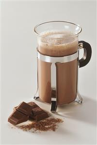 A glass of hot chocolate & two pieces of chocolate