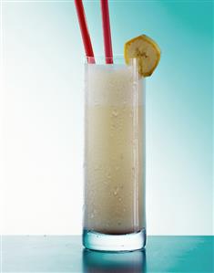 Banana milk shake in glass with straws and slice of banana