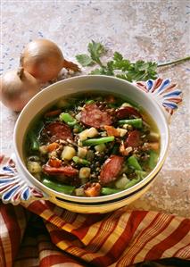 Lentil soup with sausage, beans & potatoes in soup bowl