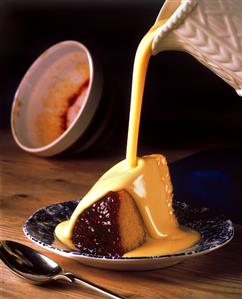 Custard running over English raspberry jam pudding