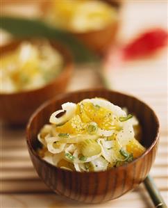 Onion & celery salad with orange pieces in wooden bowl