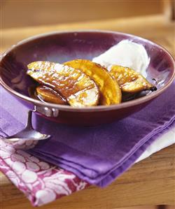 Baked, halved bananas with cream in bowl