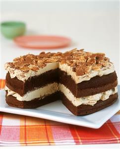 Chocolate cream gateau with flaked almonds, a piece cut