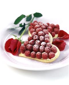 Shortbread hearts with raspberries on plate; rose. Receta disponible TR.