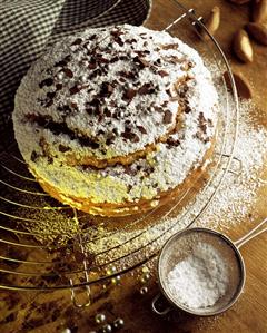 Apple & brazil nut cake being dusted with icing sugar