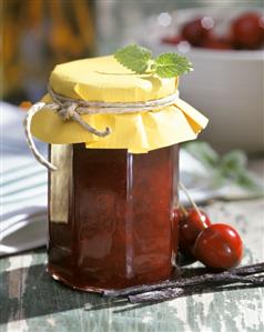 Cherry jam in a jar, with fresh cherries beside it