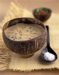 Tamarind & coconut soup with coriander & mint in wooden bowl