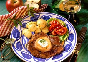 Chop with apple slice, parsley potatoes as accompaniment