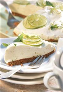 A piece of lime pie in front of pie with piece cut
