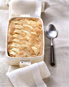 Sweet apple pudding with cinnamon in baking dish