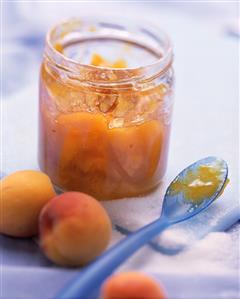 Apricot jam in jar, apricots and sugar beside it