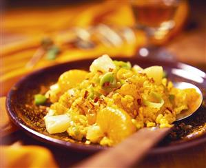 Spicy curry rice salad with orange segments, pineapple & leek