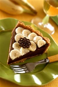 A piece of chocolate tart with banana slices on plate