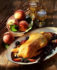 A roast duck with peach wedges and blackberries