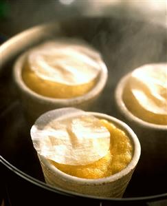 Lemon & coconut pudding in terracotta dish in bain-marie