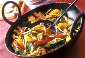 Finely chopped chicken with peppers & oranges in the wok