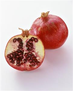 Pomegranate half in front of whole pomegranate