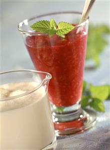 Red berry compote in dessert glass, cream in jug in front