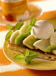 Fruit pizza, garnished with vanilla ice cream & lemon balm