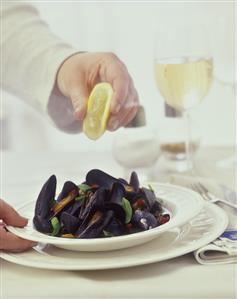 Sprinkling steamed mussels with lemon